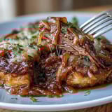 Slow-cooked Savory Crock Pot French Onion Pot Roast with caramelized onions and fresh parsley garnish.