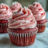 Delicious Pink Velvet Cupcakes with Vanilla Buttercream Frosting, topped with pink sprinkles on a marble counter.