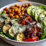 Colorful roasted vegetables and creamy hummus top this healthy Vegan Mediterranean Buddha Bowl, served on a bed of fresh mixed greens.