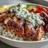 Vibrant Greek Chicken Bowl topped with juicy chicken, cucumber-tomato salad, and a creamy dollop of tzatziki.  