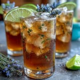 A vibrant lavender lemonade spritz with sparkling wine, garnished with fresh lemon slices and lavender sprigs in a sunny glass.