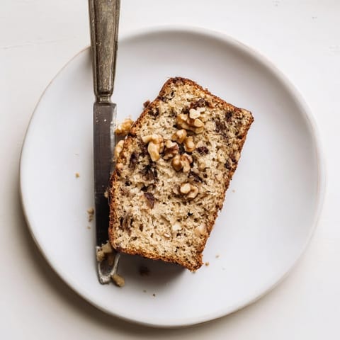 A thick slice of Banana Bread on a plate with melting butter, ready for breakfast.