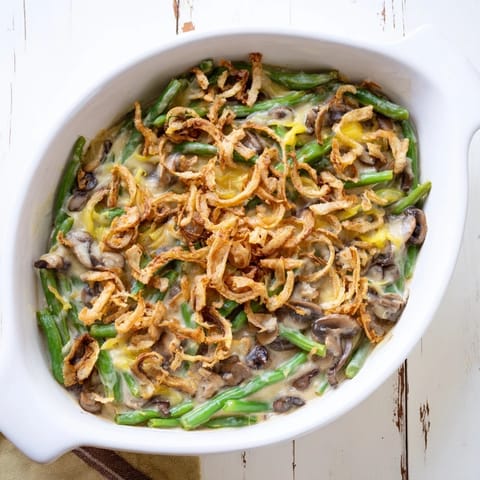 A close-up of classic Green Bean Casserole with golden brown, crunchy fried onion topping.