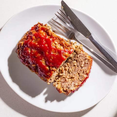 Freshly baked classic Meatloaf with a glossy, caramelized ketchup glaze, sliced thick and ready to serve alongside creamy mashed potatoes.