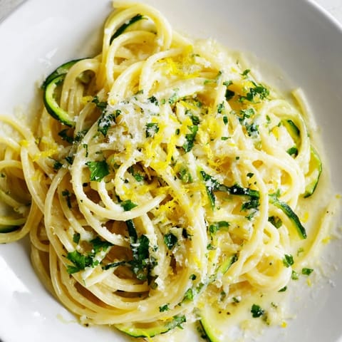 Spiralized zucchini noodles tossed with al dente spaghetti in a vibrant lemon butter sauce, topped with fresh parsley and shaved Parmesan cheese.  