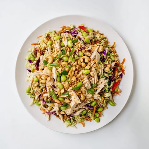 Tossing the vibrant Edamame Crunch Chicken Salad with fresh vegetables, edamame, and a zesty ginger dressing.