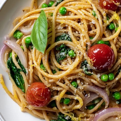 A close-up shows al dente spaghetti coated in lemon zest and olive oil, topped with Parmesan and fresh basil leaves.