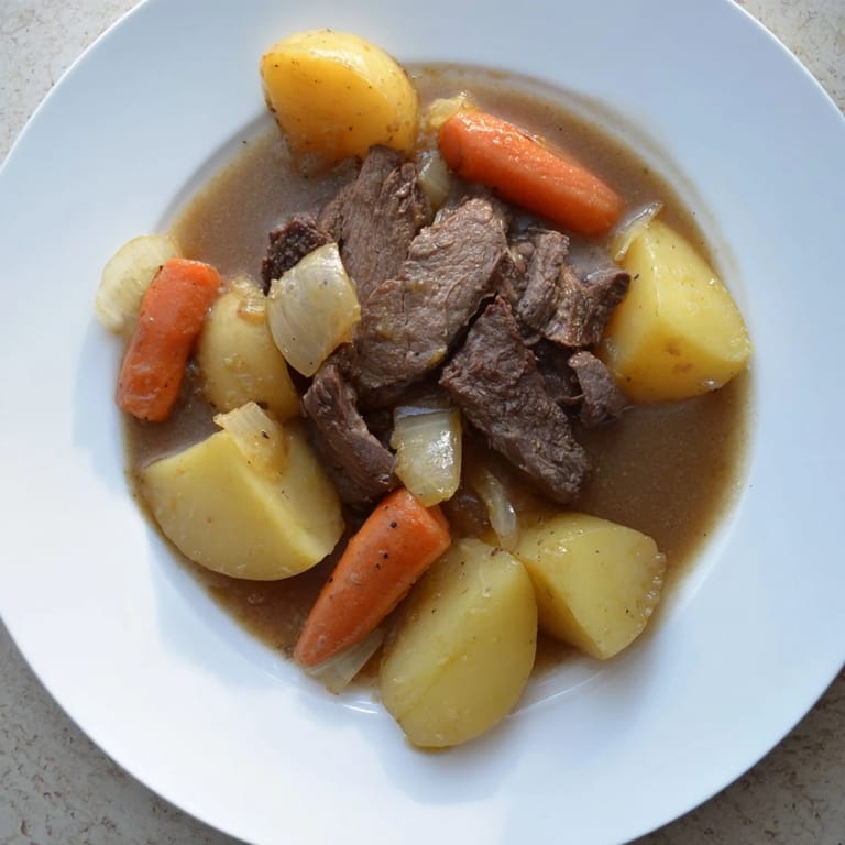 Family-style Beef Pot Roast served hot, featuring juicy beef, soft carrots, and potatoes, ready to be scooped onto dinner plates with a ladle of gravy.