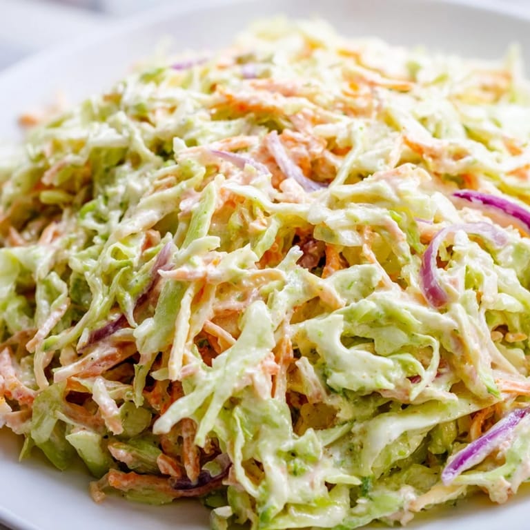 Vibrant Coleslaw with shredded cabbage, carrots, and fresh herbs in a glass bowl, served alongside grilled burgers.