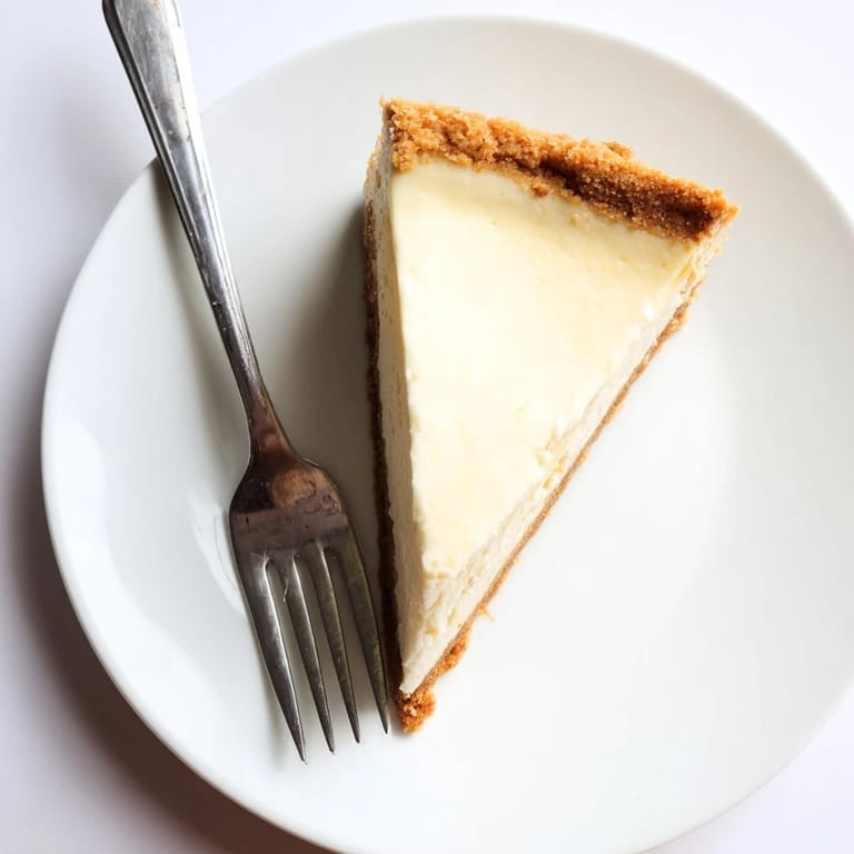 Perfectly set New York cheesecake with a smooth sour cream topping, ready to be served with fresh berries.