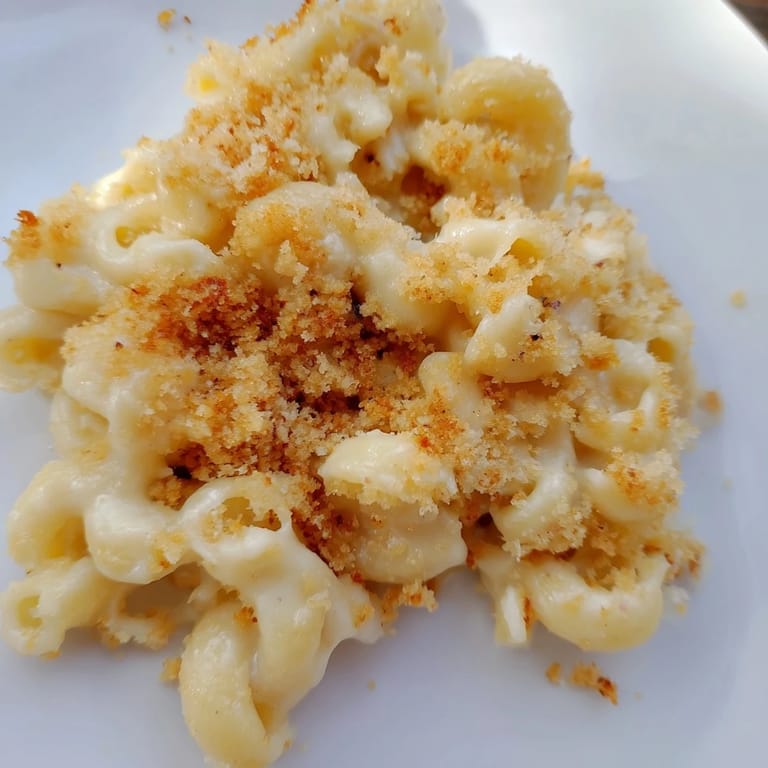 A close-up of creamy macaroni and cheese shows melted cheddar sauce clinging to tender elbow noodles.