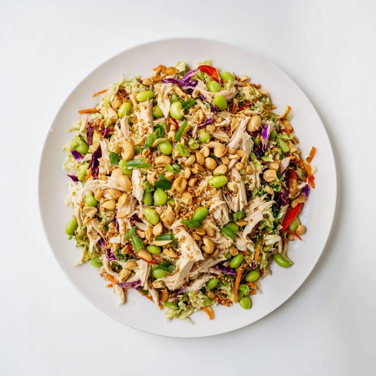 Tossing the vibrant Edamame Crunch Chicken Salad with fresh vegetables, edamame, and a zesty ginger dressing.