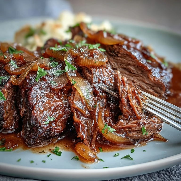 Shredded Savory Crock Pot French Onion Pot Roast served over mashed potatoes with melted Gruyere cheese.