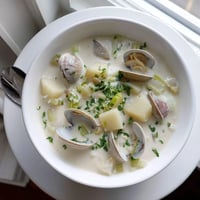 Creamy New England Clam Chowder served hot in a rustic bowl, garnished with fresh parsley and oyster crackers.