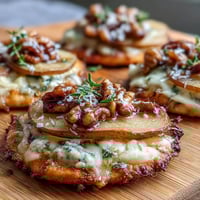 Crisp mini pizza rounds topped with sweet pear slices, creamy Gorgonzola, and tangy pickled walnuts, served warm.