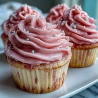 Freshly baked Pink Velvet Cupcakes with Vanilla Buttercream Frosting on a cooling rack, showing moist crumb.